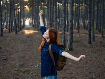 Full length of woman standing on field in forest