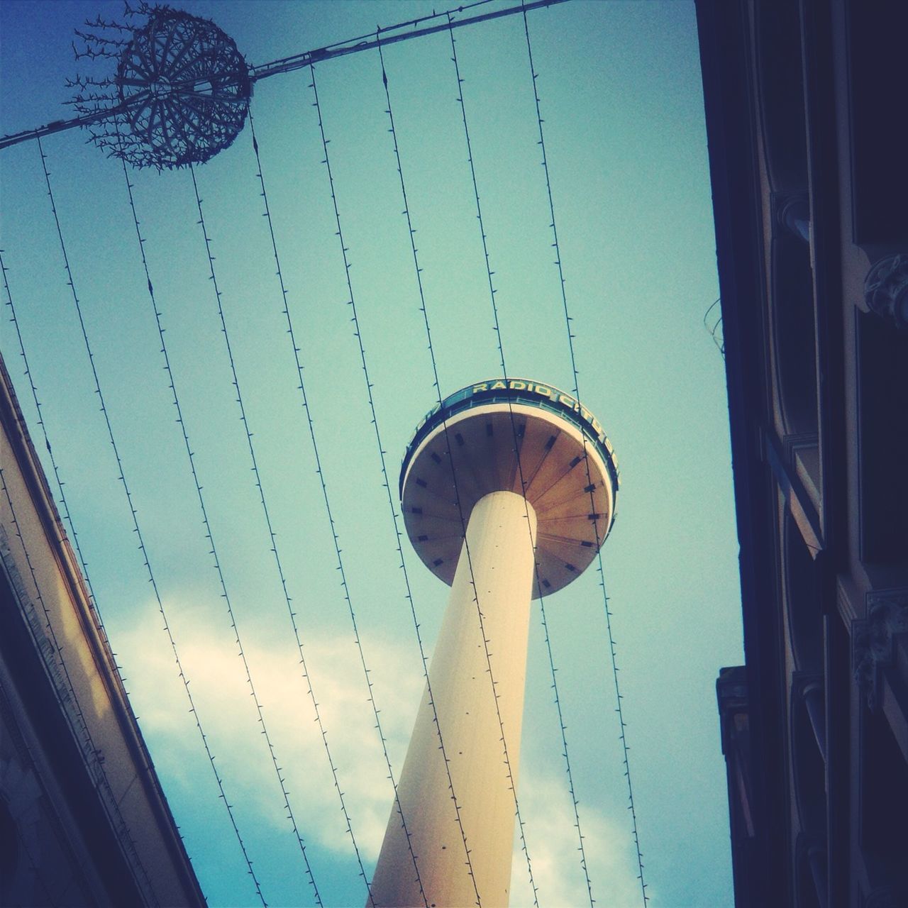 low angle view, built structure, architecture, blue, sky, building exterior, tall - high, clear sky, amusement park, ferris wheel, metal, city, outdoors, arts culture and entertainment, tower, amusement park ride, connection, no people, street light, day