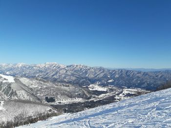 Scenic view of snowcapped mountains against clear blue sky