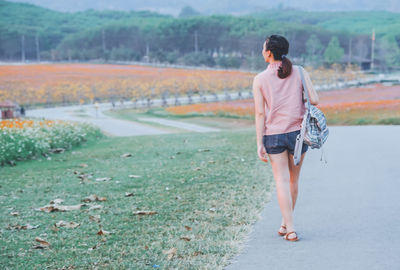 Rear view of woman standing on road at park