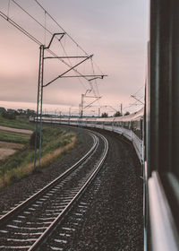 Train on railroad track against sky at dusk