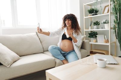 Young woman using laptop while sitting on sofa at home