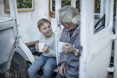 Senior man and boy having a coffee break at vintage car