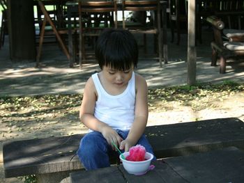 Boy eating flavored ice while sitting on table