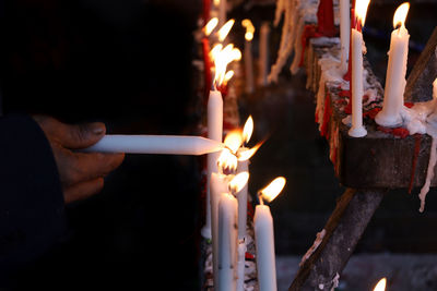 Human hand holding lit candles in temple