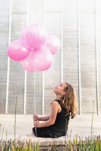 Side view of woman with pink balloons