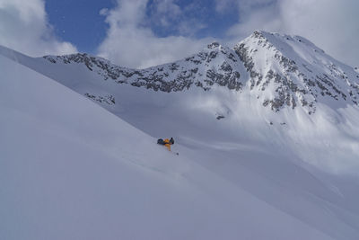 Person skiing on snowcapped mountain against sky