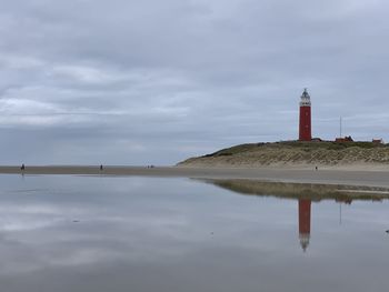 Lighthouse by building against sky