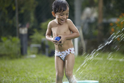 Happy boy standing in bathtub on grass at back yard