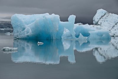 Scenic view of glaciers on lagoon against cloudy sky