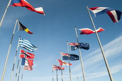 Low angle view of various national flags against blue sky