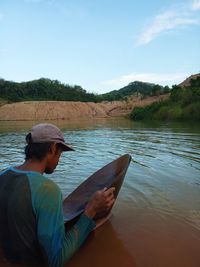 Side view of man in lake against sky