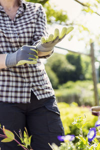 Midsection of woman wearing gloves at community garden