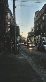 Cars on city street against sky