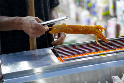 Cropped hand of man working on barbecue grill