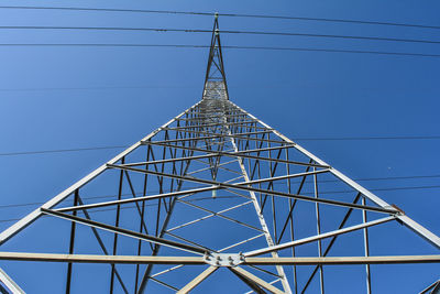 Low angle view of electricity pylon against blue sky