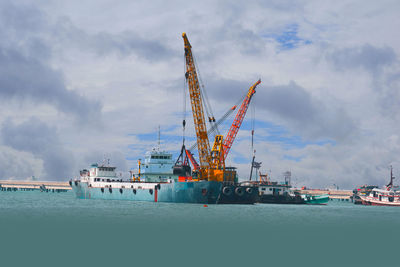 Cranes at commercial dock against sky