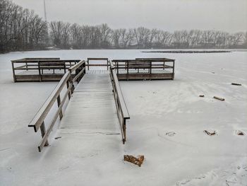 Empty benches on snow covered landscape during winter