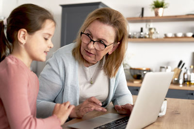 Grandmother and granddaughter using laptop