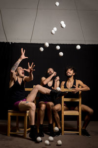 Young jugglers sitting on chairs with balls on stage