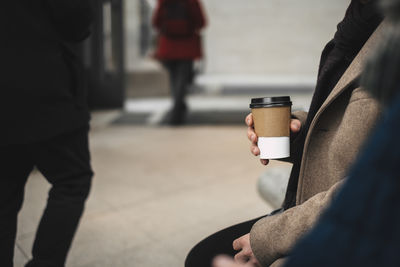 Midsection of man holding coffee cup