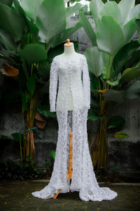 White wedding dress on a mannequin captured in an outdoor garden.