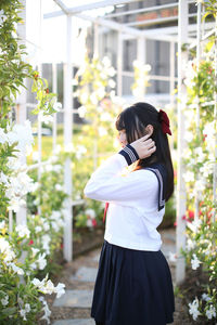 Full length of woman standing against white flowering plants