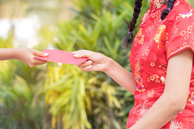 Cropped hand giving envelope to woman in park