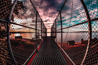 Bridge against sky seen through chainlink fence