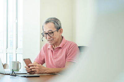 Young man using mobile phone while sitting on table