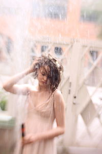 Girl holding garden hose while standing outdoors