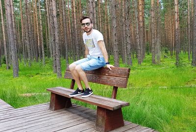 Full length portrait of young man sitting on bench