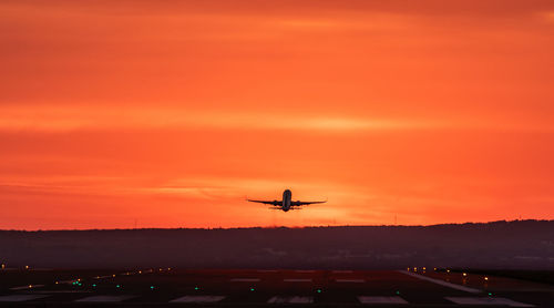 Airplane flying against orange sky