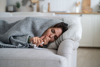 Midsection of woman lying on sofa at home