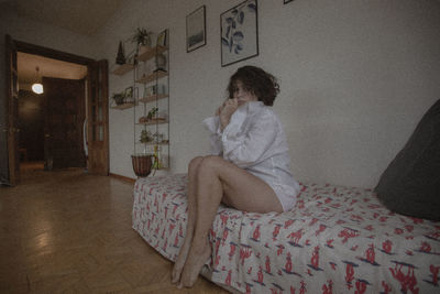 Rear view of woman sitting on bed at home