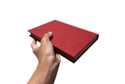 Close-up of hand holding book against white background