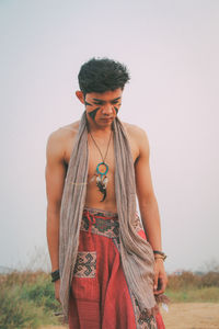 Young man standing on field against clear sky