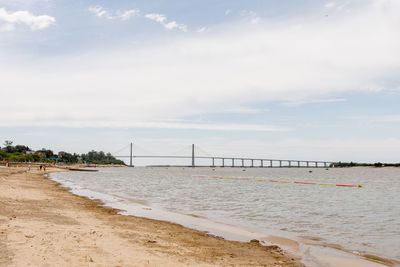 Bridge over sea shore against sky