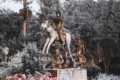 Statue amidst plants against trees