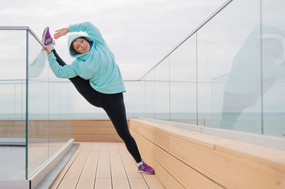 Full length of young woman exercising in gym