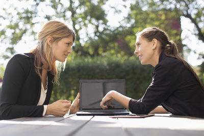 Businesswoman discussing with female colleague through laptop at outdoor cafe