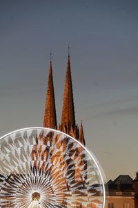 Low angle view of illuminated ferris wheel against building
