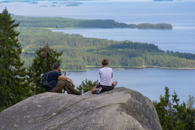 Rear view of men sitting on rock looking at view