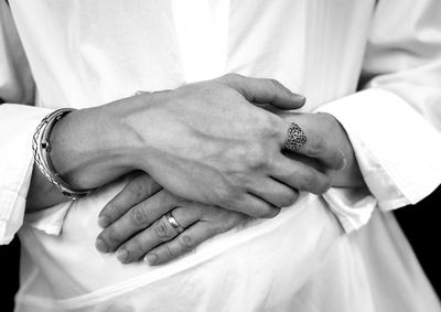 Midsection of bride showing rings with hands clasped