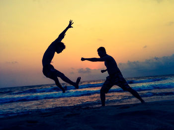 Silhouette of people on beach at sunset