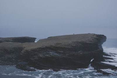 Rock formations by sea against clear sky