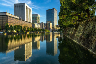 Skyscrapers of downtown tokyo reflected in water of the canal around tokyo imperial palace, japan