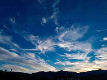 Low angle view of silhouette mountains against blue sky