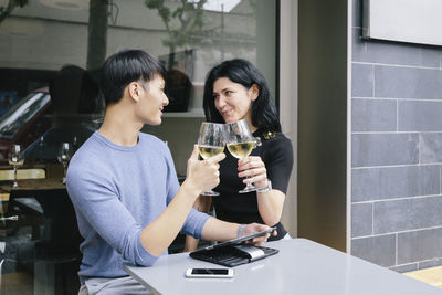 Couple toasting drinks while sitting at sidewalk cafe