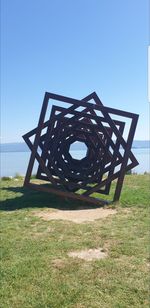 Metallic structure on field against clear blue sky